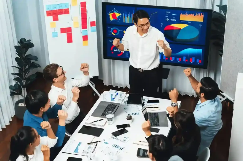 Digital Marketing Companies in the Philippines celebrate a successful marketing campaign, showing teamwork and positive results in a modern office meeting.